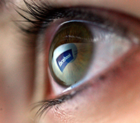 Eye reflectting a Facebook logo